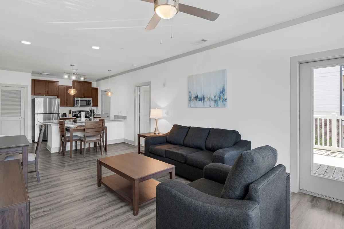 An open-concept space featuring a stylish sofa, dining table, kitchen area, and prominent artwork. The room is airy and inviting, with carefully chosen decor that exudes sophistication and comfort.