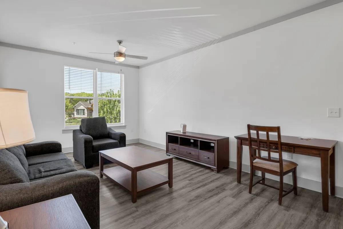 A cozy seating area with a comfortable chair, coffee table, desk, and chair, accented by bright windows. The inviting design is elevated by functional elements, blending style and utility at the entry point.