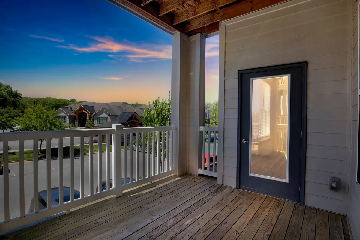 An exterior shot from the balcony shows a scenic neighborhood view beyond the railing, with the gentle suggestion of sunrise or sunset. The peaceful setting invites moments of relaxation, perfect for unwinding after a day exploring the city.