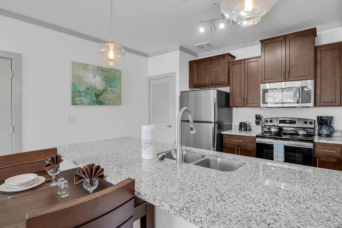 A contemporary kitchen featuring a central island, stainless steel appliances, and an eye-catching art piece on the wall. The scene is set for cooking, entertaining, or enjoying a quiet moment, with a warm, urban vibe that reflects the apartment’s location in the heart of Knoxville.