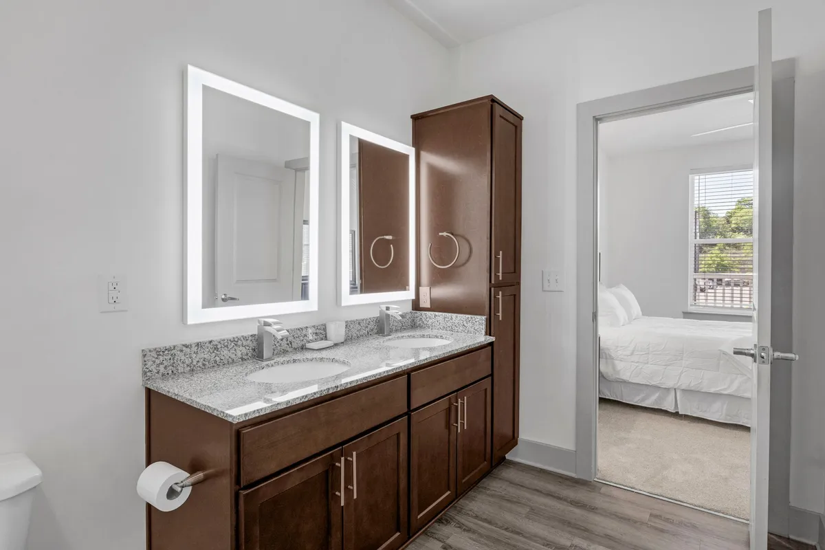 A fresh, contemporary bathroom with a double vanity, sleek granite countertops, modern mirrors, and ample storage. The space is well-lit and designed for both functionality and indulgence, ideal for morning or evening routines.